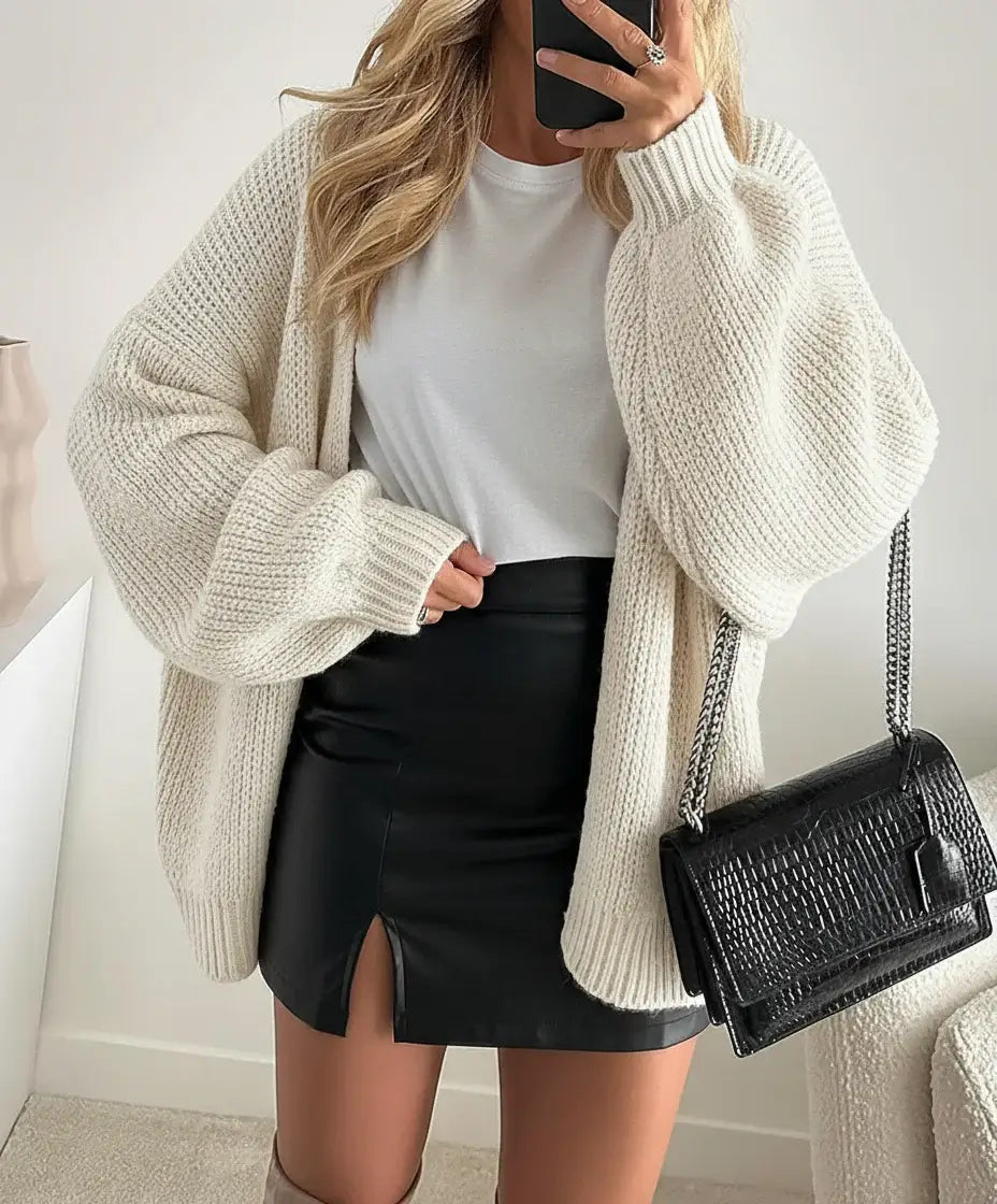 A woman wearing a Comfy Oversized Cardigan over a white t-shirt and a black skirt, showcasing effortless style.
